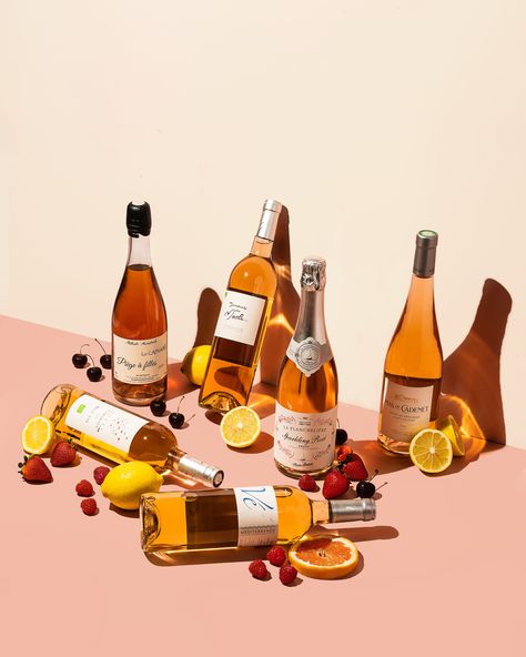 Six wine bottles are scattered on a pink and cream background, some laying down while others stand or lean. The fruit placed beside including strawberries, raspberries, lemons and cherries represent the tasting notes of the wines. Alcohol Shot, Beverage Photography Ideas, Wine Bottle Photography, Bottle Shoot, Brisbane Airport, Wine Glassware, Wine Rose, Still Life Pictures, Drinks Photography