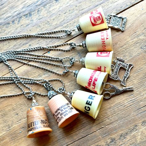 Our vintage thimble necklaces are back! I have so much fun sourcing these vintage and antique thimbles from flea markets and antique stores. We're giving them a new life! Each unique thimble necklace includes one plastic vintage thimble with some advertising on it, with a rhinestone rondelle and tiny repurposed bead. Some will feature a charm of either a sewing machine, embroidery scissors, or a little charm that says "I Love Quilting". PLEASE NOTE: These sweet necklaces are made of true vintage Thimble Crafts Ideas, Thimble Jewelry, Thimble Necklace, Thimble Art, Antique Thimbles, Upcycle Jewelry, Buttons Crafts Diy, Crafty Jewelry, Key Necklace Vintage