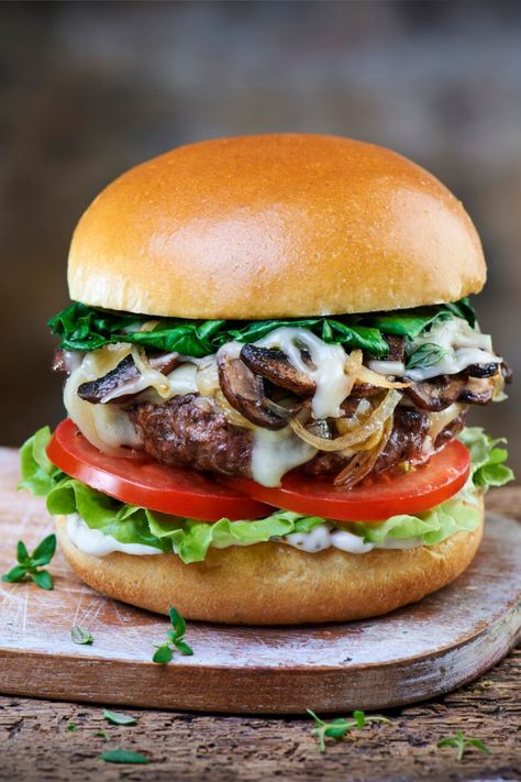 A beef burger on a wooden board on a table. Luxury Burger, Burgers With Mushrooms, Mushroom Cheeseburger, Goat Cheese Burger, Truffle Mayo, Brioche Burger Buns, Truffle Burger, Mushroom Swiss Burger, Cheese Burgers