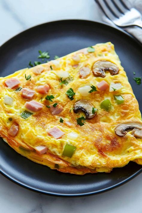 This classic Denver omelette will make you jump out of bed! With peppers, ham, onions, mushrooms, and cheese, it's a savory way to start the day. Omlette Cheese Sandwich, Simple Omelette Recipe, Denver Omelette, Ham And Cheese Omelette, Omelette Breakfast, Omlet Recipes, Omelette Recipe Easy, Breakfast Omelette, Foods Ideas