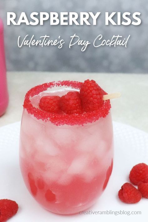 Raspberry kiss cocktail for Valentine's Day. This pink raspberry cocktail recipe is easy to make, garnished with red sugar and raspberries.  Make this Valentine's day raspberry cocktail. #valentinesday #recipe #drink #cocktail Valentines Drinks Alcoholic Punch, Non Alcoholic Galentines Drink, Valentine’s Day Vodka Drinks, Valentines Cocktails Vodka, Pink Valentines Cocktails, Vodka Valentines Drink, Tequila Valentine Drink, Romantic Drinks For Two, Easy Galentines Cocktails