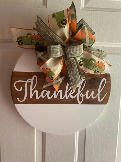 Thankful fall sign is white with stain with "thankful" wording and matching fall theme bow! *Sign can be personalized to your word or phrase of your choosing. If no personalization is requested the sign will come with "thankful." *Other color variations can be made upon request. Door Hanger: *Round Pine Board (may be wood variations) *Size: 15" or 18" *Paint color: white * Stain color: Early American *Sign is sealed for protection * Permanent vinyl lettering (each sign could vary, depending on w Round Thanksgiving Door Hanger, Diy Wooden Circle Sign, Fall Door Hangers Diy, Autumn Signs, Fall Round Wood Signs, Round Signs, Fall Door Hangers Wooden, Round Wood Signs, Thankful Crafts