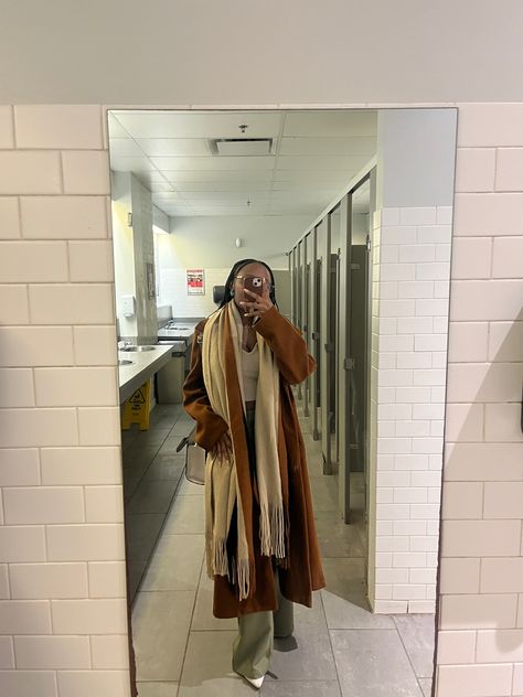 A beautiful young black woman taking a mirror selfie in an empty restroom. Her outfit is really cute. She has on green pants, t-shirt (idk what colour it is. It’s like an ashy camo green-grey colour?), darker cinnamon-brown trench coat, brown scarf, grey bag, and white boots. Brown Trench Coat, Brown Scarves, Grey Bag, Green Pants, White Boots, Camo, Gray Color, Green And Grey, Trench Coat