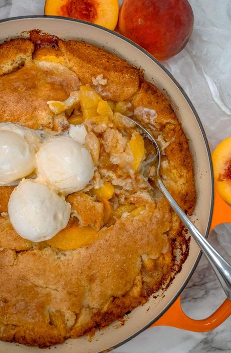 A spoon digging into a juicy peach cobbler baked in a Dutch oven. Oven Peach Cobbler, Dutch Oven Peach Cobbler, Fresh Peach Cobbler, How To Peel Peaches, Fluffy Cake, Baked Peach, Comfort Desserts, Juicy Peach, Fruit Cobbler