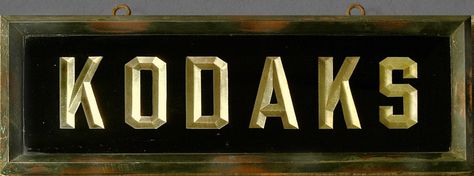 This sign is about 9"X24". A copper frame holds two back to back glass panels with reverse gold leaf letters advertising KODAKS. The typography and construction suggest it is c.1910.  We have been unpacking our Kodak advertising memorabilia to hang in the the garage/studio but we have decided that this sign is too special and it will hang from our entry hall ceiling. Hall Ceiling, Gold Leaf Signs, Painting Lettering, Sign Painting Lettering, Sign Inspiration, Gold Sheets, Garage Studio, Sign Painting, Window Signs