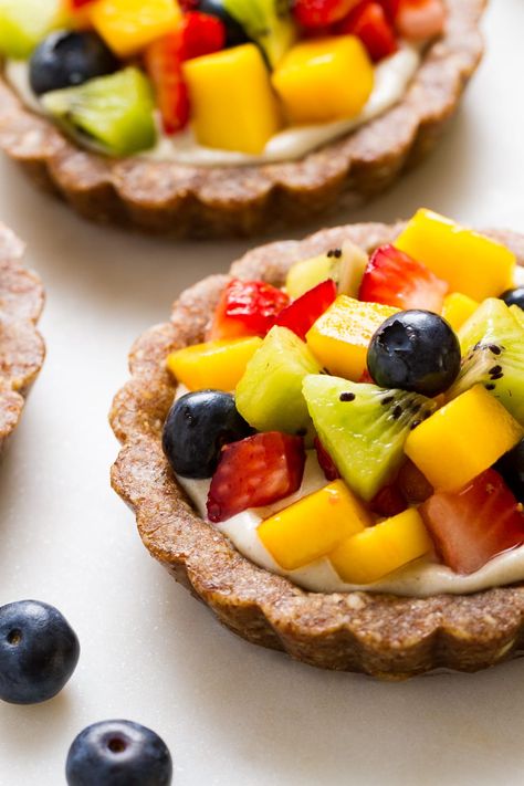 Raw Vegan Fruit Tarts - A delicious no-bake fruit tart recipe featuring an almond crust, creamy cashew sweet cream and topped with lot's of fresh, colorful fruit! Healthy, gluten-free vegan dessert.