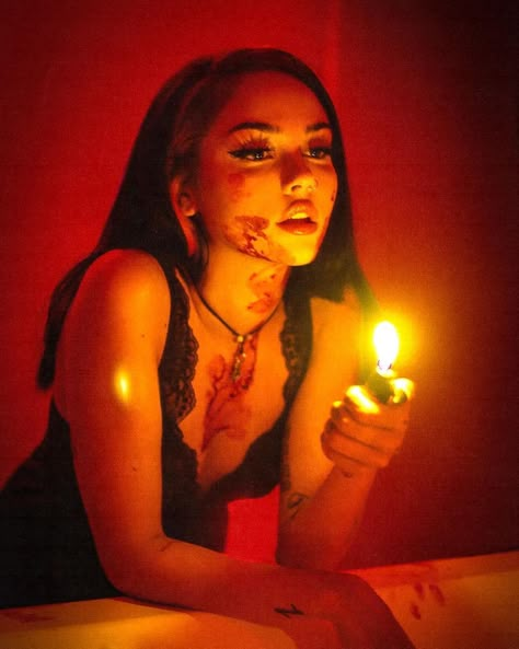 maggie lindemann, a singer/celebrity, leans in front of a mirror in a darkly lit room. she is holding a lighter in front of her face, casting the room in a red/orange glow. she has smears of blood on her face, neck, and chest. The Human Centipede, Jennifer’s Body, Spooky Ideas, Maggie Lindemann, Dark Feminine Aesthetic, Halloween Photoshoot, Foto Poses, Birthday Themes, Photoshoot Concept