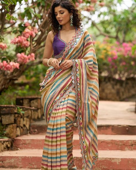 Upgrade your saree collection with our stunning multicolor striped printed saree, featuring elegant bold mirror work embroidery. Perfect for any occasion, this saree will make you stand out with its unique design and eye-catching colors. Elevate your style and make a bold statement with this one-of-a-kind saree. #sujatra #sujatraglobal #sujatrasarees #stripedsaree #printedsaree #multicolor #multicolorsaree #mirrorwork #mirrorembroidery #embroideredsaree #modernsaree Multicolour Saree, Multi Colour Saree, Mirror Work Embroidery, Saree Material, Floral Print Sarees, Modern Saree, Flowy Fabric, Printed Saree, Pretty Jewelry