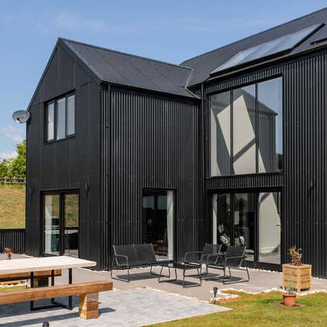 Cladco Corrugated Roofing and Cladding Sheets have been used to create a low-maintenance exterior for this fantastic self-build, nestled within the Devon countryside. A PVC Plastisol Coating in Black has been used to finish the sheets, contributing to the build's unique, robust character. Custom-made Flashings have been skillfully applied to enhance the aesthetics and function of doors and windows. Want to learn more about this incredible project? Check out our Youtube channel. Black Corrugated Cladding, Coloursteel Cladding, Devon Countryside, Cladding Sheets, Cladding Ideas, Corrugated Metal Wall, Exterior Finishes, Bespoke Home, House Cladding