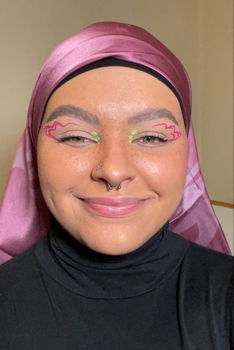 Girl wearing a pink head scarf with pink and green graphic eyeliner Pink Neon Eyeliner, Green Eyeliner Graphic, Pink And Green Graphic Liner, Spring Eyeliner Looks, Pink And White Graphic Liner, Pink And Green Eyeliner, Fun Liner Looks, White And Pink Eyeliner, Eyeliner Looks Colorful