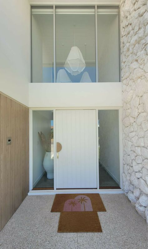 This lovely white Torbay pivot door has a streamlined, modern profile. The entry door features solid timber battens with bold, negative details and wide shadowlines. This stunning door is over 2.3m tall! 
Designed and built by Riverstone Homes
Torbay door and frame by Cedar West
Find out more about our Modernstyle doors here: https://cedarwest.com.au/products/doors/door-designs/modernstyle-doors Wide Bedroom Door, White Pivot Front Door, Coastal Entry Door, Timber Entry Door, Solid Front Door Ideas, Modern Coastal Front Door, White Entrance Door, Front Door Ideas Entrance, Coastal Front Door