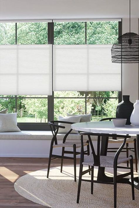 A dining room interior showing windows covered with white honeycomb 'top down/bottom up' blinds. They can be adjusted either from the top or bottom to give maximum flexibility to cut glare. Metal Storage Buildings, Bay Window Treatments, Window Remodel, Pleated Blinds, Cellular Blinds, Blinds Design, Thermal Blinds, Honeycomb Blinds, Pleated Blind