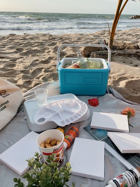 Beach picnic, with painting materials as canvas, paint, brushes, ice chest with cold drinks, and flowers Beach Picnic Painting, Beach Paint And Sip, Painting On The Beach Date, Paiting Aesthetic Date, Picnic Beach Ideas, Picnic Painting Ideas, Beach Date Ideas, Beach Picnic Ideas, Painting Picnic