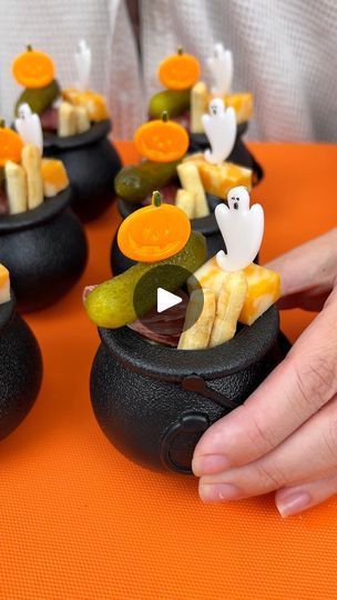 Easy spooky appetizer! | Easy spooky appetizer!  I make mini charcuterie cups for a halloween party. | By Justine Kameron | I added some unshelled pistachios to my mini cauldrons. I'm next coming in with a ghost toothpick and I'm putting some Colby Jack, a blueberry, and some white cheddar on my ghost toothpick. We're going to place that right inside the cauldron with our pistachios just like so. This is going to be so cute for halloween. Everyone will love this. Next, I'm coming in with a pumpkin toothpick and for this one, we are going to add a baby dill and then I'm going to grab my salami and I'm going to fold it twice and then it'll be perfect size to go on the toothpick with our baby dill. Next I'm adding a garlic olive and then this toothpick is being placed right next to our ghost Toothpick Appetizers Halloween, Cauldron Snack Ideas, Halloween Individual Charcuterie Cups, Pumpkin Charcuterie Cups, Food On A Toothpick, Halloween Veggie Cups, Halloween Mini Dessert Cups, Ghost Theme Party Food, Halloween Charcuterie Cups Ideas