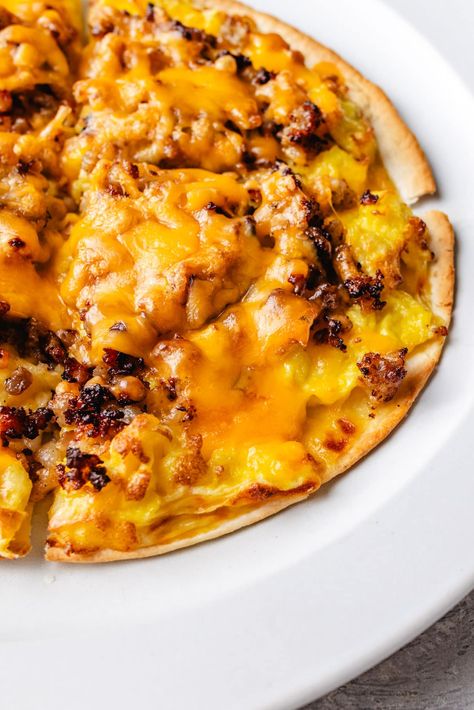 Enjoy a protein-packed start to your day with this delicious Breakfast Pizza Recipe. Featuring low-carb tortillas as our pizza crust, a cheesy, creamy sauce, scrambled eggs, crumbled sausage, shredded cheese, and any extra toppings you desire. High Protein Breakfast Pizza, Tortilla Breakfast Pizza, Egg Pizza Breakfast, Breakfast Pizzas, Protein Pizza, Egg Pizza, Breakfast Pizza Recipe, Tortilla Shells, Egg Protein