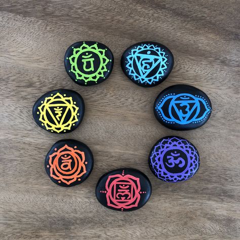 This is the unique set of seven hand painted chakra meditation stones with the traditional Sanskrit chakra symbols. The stones are painted with black acrylic paint and are maken 7 chakra symbols in rainbow colors on them. This adorable Chakra stone set comes with a small tulle bag for easy storage and travel for an energy boost or alignment when needed. Spiritual Rock Painting Ideas, 7 Chakra Symbols, Chakras Stones, Meditation Crafts, Chakra Painting, Chakra Decor, 7 Chakra Stones, Spiritual Paintings, Diy Rock Art