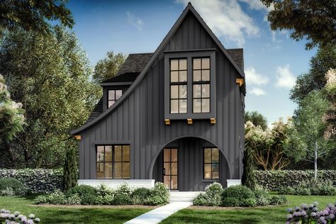 Dramatic swooping roof lines and an arched entryway catch the attention of those passing by this Contemporary Tudor home plan that is exclusive to Architectural Designs.French doors near the foyer open to a home office, across from a guest suite with a built-in bench tucked beneath the window.The open layout combines the great room, island kitchen, and dining area, and a 9' by 11'6" covered porch is ideal for grilling or dining outdoors.Three bedrooms and the laundry room reside upstairs, with t Modern Tudor Exterior, Contemporary Tudor, Arched Entryway, Tudor House Plans, Tudor Home, Kitchen And Dining Area, Tudor Style Homes, Roof Lines, Tudor House