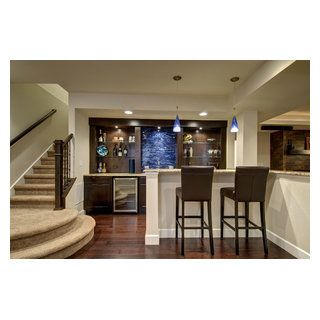 Walk behind wet bar with wood floors, glass shelves, built in wine cooler and blue accent tile. ©Finished Basement Company L Shaped Bar Basement, Lower Level Bar, Transitional Basement, Built In Wine Cooler, Home Bar Areas, White Tile Backsplash, Basement Inspiration, Home Bar Design, Basement House