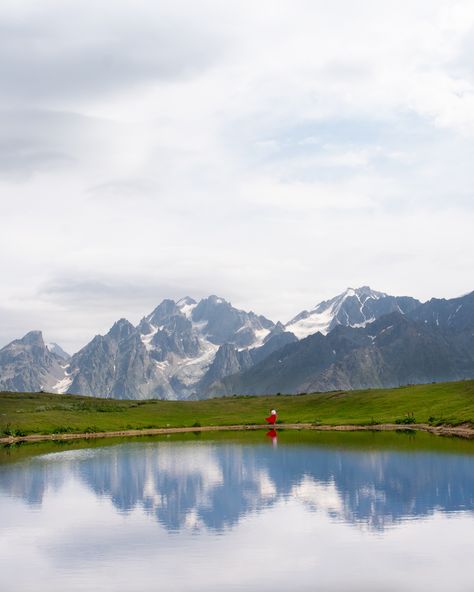 Girl in a red skirt standing at the edge of the lake with a background of mountain reflecting in the lake Places To Go In Georgia, Mestia Svaneti, Mestia Georgia, Country Georgia, Svaneti Georgia, Georgia Caucasus, Georgia Travel Guide, Day Trips From Prague, Azerbaijan Travel