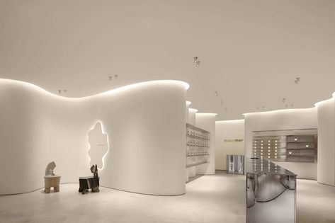 The new oriental original aromatherapy brand "ToSummer" announces its first off-line flagship store, the "ToSummer living room", located on the ground floor of Taikoo Li North District, Sanlitun, Beijing. With its inviting combination of streamline and curved surfaces, the design transforms the 170m² space while leading visitors to naturally follow a circular flow. With the extensive use of mirror effects combined with continued light, naturalistic materials, and colors to enhance the ambiance o Faux Stone Walls, Retail Space Design, Retail Lighting, Architecture Magazines, Curved Walls, Retail Interior, Installation Design, Retail Space, British Design