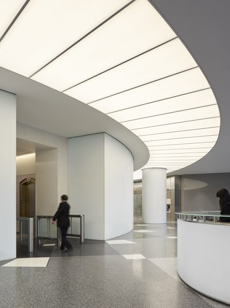 A substantial renovation of the iconic US Bank Tower in downtown Los Angeles by new owners OUE included this spectacular lobby upgrade. A luminous arc provides a focal point for the reception area beneath a large digital art display and the illumination delivered acts as a comfortable transition from daylight into the interior while providing wayfinding to the elevator area for visitors. ARCHITECT: Gensler / LIGHTING DESIGN: Lighting Design Alliance / Photo: ©Gensler/Ryan Gobuty #lighting #light Lobby Lighting Design, Luminous Ceiling, Us Bank Tower, Aesthetic Lighting, Lobby Lighting, Us Bank, Building Lobby, Interior Design Layout, Design Strategies