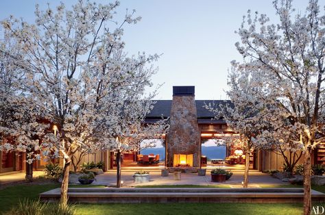 A fireplace anchors a courtyard off the great room of Dana Johnson and Mark Nelson’s 10,000-square-foot residence. They commissioned architect Howard J. Backen to create the house and a winery on the 300-acre property in Napa Valley. Mark W. Bowers was the landscape architect. Winery Ideas, Rustic Home Exterior, Country Interior Design, Outdoor Fireplace Designs, Modern Country Style, Country House Design, Country House Interior, Wine House, Country Interior