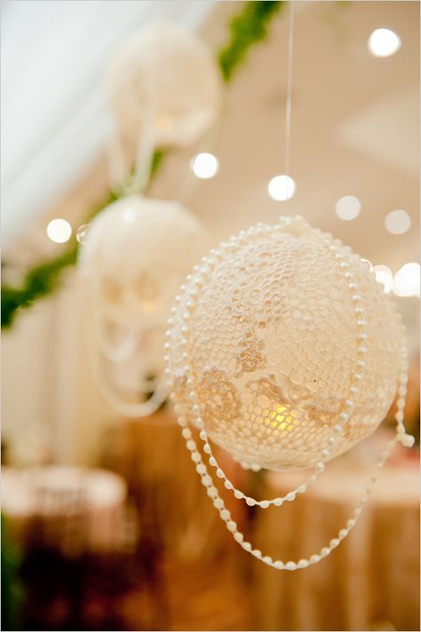 The lanterns are made by overlapping lace doilies on an inflated balloon and brushing fabric stiffener (or wallpaper glue, or even white glue) onto the doilies. Be sure to cover it completely so that the whole thing hardens and you aren’t left with limp spots. Let the doilies dry overnight to ensure that they are completely dry. The last step is to pop the balloon and pull it out of the opening. The lanterns can be hung with a ribbon or fishing line draped with strands of beads..