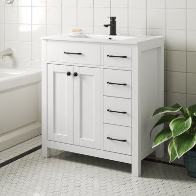 This single vanity set brings contemporary style and plenty of storage to your main or guest bathroom. The freestanding base is made from engineered wood with a crisp white or black finish, and it rests on slim legs that keep sightlines clear. Its ceramic white countertop complements the rectangular sink and gives you plenty of space for your must-have toiletries. Three drawers and two doors open to reveal room for everything from towels and makeup to hair products and cleaning supplies. We love 35 Inch Bathroom Vanity, 30 Inch Bathroom Vanity White, White Vanity Bathroom Black Hardware, Bathroom Vanity 30”, 30 Inch Vanity Bathroom, Small Bathroom Vanity Ideas, 30 Inch Vanity, 30 Inch Bathroom Vanity, White Countertop