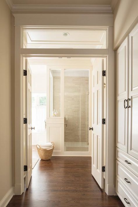 A transom window is located above white double doors opening to a master a bathroom fitted with a wood floor leading to a walk-in shower. Double Door Entryway, Wood Floor Bathroom, Double Door Entrance, Small Bedroom Remodel, White Wood Floors, Double Door Design, Cottage Bathroom, Bedroom Remodel, Transom Windows