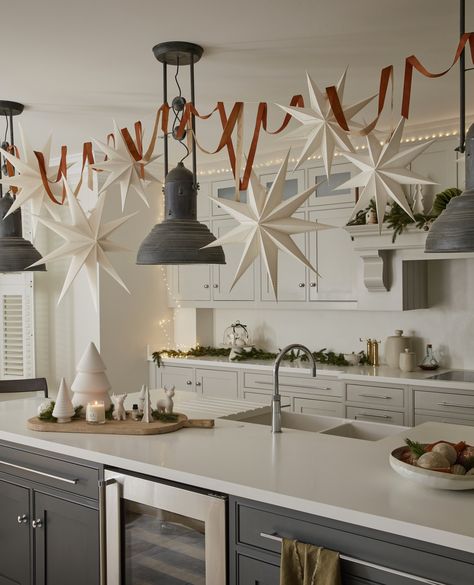 Decking out your kitchen for Christmas can be tricky. Grab some paper stars, fishing twine and command hooks, and let them stars dangle gracefully from the ceiling. Placing some fairy lights around the top of the room can also add a touch of easy magic. #christmas #christmaskitcehn #christmashome #layerdlounge Star Christmas Decorations, Christmas Ceiling Decorations, Cozy Houses, Christmas Star Decorations, Easy Magic, Xmas Deco, Christmas Inspo, Office Christmas, Minimalist Christmas