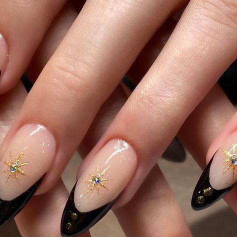 Christie Rhae Gibson on Instagram: "Classic black French with gold chrome ❤️ #nails #chiconails #nailart #chicostate #blackfrenchnails #almond #goldchrome #starburst" Black And Gold Nails Stars, French Nails With Gold Stars, Black French Tip Nails With Jewels, Black Gold French Tip Nails, Almond Nails With Gold Design, Black French With Gold, Black Tip Nails With Design, Black And Gold Nails Almond, French Tip With Nail Art