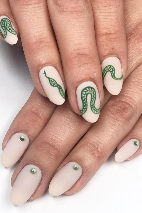 Stylish and Snakesational: Matte beige oval nails elevate the green nail game with hand-painted snake art and dainty green charms. Embrace the reptilian allure and add a touch of charm to your nails! // Photo Credit: Instagram @bluesy_nails Matte Snake Nails, Nails Vine Design, Nails With Two Designs, Simple Snake Nails, Nail Ideas Snake, Beige Oval Nails, Anti Christmas Nails, Snake Nail Art Design, Nail Art Stamp