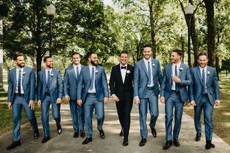 Groom in Classic Black Tuxedo with White Boutonniere | Groomsmen in Matching Blue Suits with Blue Ties | Menswear Wedding Attire Groom Black Suit Groomsmen Navy, Blue Suit Groom Black Suit Groomsmen, Blue Groomsmen Suits Color Schemes, Groom Suit Different From Groomsmen, Bridesmaid Dresses That Go With Navy Suits, Blue Groom Black Groomsmen, Blue Groomsman Suit, Groomsmen Blue Tie, Black Tux Groom Blue Suit Groomsmen