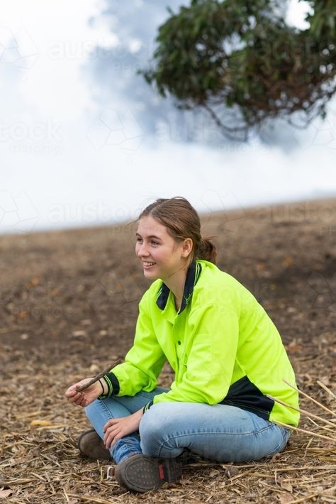 Young woman in hi-vis sitting on the ground with smoky background : Austockphoto Person Sitting On Ground Reference, Person Sitting On Ground, Sitting On The Ground Pose, Sitting On Ground Poses, Sitting On Ground Reference, Comic Poses, Sitting On Ground, Smoky Background, Pose Study