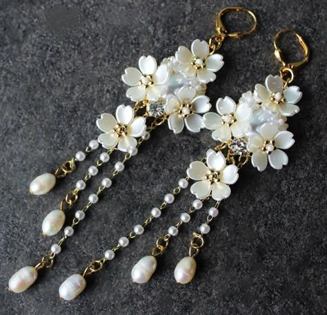 This is a statement earrings. Elegant, opulent, and shimmery, this show stopping earrings feature a soft, rich palate. The bottom fringe features three strand of small white freshwater pearls. Dangle off a sculpted white shell flowers cluster jeweled with Swarovski Crystals, plated in gold. This earrings measure 4" in length. Earrings are light weight and sway gracefully as you move about your day. These luxury earrings are bold and beautiful, and make a powerful statement. These stunning chande Wire Jewelry Earrings, Shell Flowers, Pretty Jewelry Necklaces, Luxury Earrings, Crystal Dangle Earrings, Clay Jewelry Diy, Earrings Elegant, Classy Jewelry, Wedding Formal