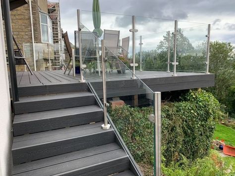 platform raised decking in black composite decking boards with a stainless steel post and glass pane balustrade system. Decking Glass Balustrade, Raised Decking, Hot Tub Landscaping, Glass Hardware, Grass Artificial, Outdoor Look, Raised Deck, Glass Fence, Glass Balcony