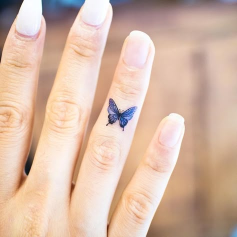 Dainty Little Blue Butterfly Tattoo on Finger - A Symbol of Joy and Freedom Blue Finger Tattoo, Small Butterfly Hand Tattoo, Finger Butterfly Tattoo, Butterfly Tattoo On Finger, Mini Butterfly Tattoo, Finger Butterfly, Explore Images, Small Butterfly Tattoos, Tattoo On Finger