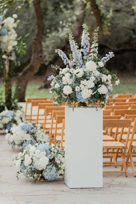 We loved using a blend of classic white flowers with pops of blue for this December wedding!  We incorporated white roses, anemones, tweedia, delphinium, hyrangea, ranunculus, spray roses, and beautiful greenery to bring these designs together.🤍 | Flowers by @florafetish | Photography by @aprilmaecreativ | #whiteweddingflowers #weddingflowers #whitebridalbouquet #weddingflorist #weddingcenterpiece #bridalbouquet #bridesmaidbouquet #weddingfloral #aisledesign #luxuryweddingflowers #weddingarch Blue Aisle Flowers, Blue Floral Arch Wedding, Blue And White Flowers For Wedding, Wedding Pillars Ceremony Floral Arrangements, Floral Wedding Ideas Decor, Blue And White Aisle Arrangements, Greenery And Blue Wedding, Blue Wedding Ceremony Decor, Blue And White Ceremony Flowers