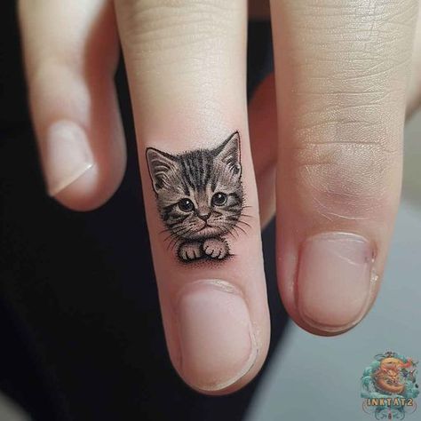 The counterpart to the previous image, this tattoo portrays a serene kitten, its fur patterned with delicate shading. The kitten's eyes are filled with innocence, making this tiny tattoo a sweet and endearing choice for cat lovers. Find your next adorable design at inktat2.com and don't forget to follow us for daily doses of cuteness. Feminine Finger Tattoos, Cat Face Tattoo, Tattoos For Women Cat, Tiny Cat Tattoo, Cat Face Tattoos, Kitten Tattoo, Katt Grejer, Tato Minimal, Finger Tattoo Designs