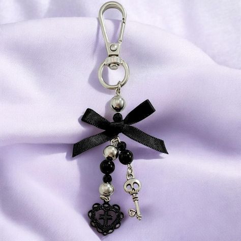 Embrace the dark and alluring world of gothic fashion with this stunning key pendant keychain, designed specifically for those who appreciate the blend of elegance and edge. This unique accessory features a striking combination of a gothic cross, love heart, and skull, all brought together with a delicate black bow, making it the perfect statement piece for your keys, bag, or even as a distinctive jewelry piece. Crafted with meticulous attention to detail, this keychain embodies the essence of dark coquette style, blending romantic elements with a touch of the macabre. The pendant's intricate design reflects the Y2K era's fascination with bold and expressive accessories, while the black and silver tones add a timeless gothic vibe. Ideal for women who want to make a bold fashion statement, Dark Coquette Accessories, Gothic Keychain, Coquette Keychain, Goth Keychain, Y2k Halloween, Gothic Mode, Black Keychain, Skull Keychain, Pendant Keychain