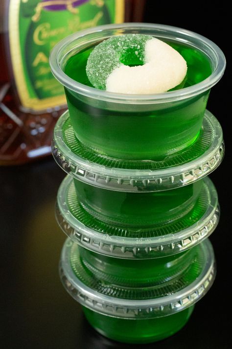 Four 2oz portion containers filled with Crown Apple jello shots are stacked on top of one another in front of a bottle of Crown Apple. Green Apple Fireball Jello Shots, Fairy Jello Shots, Apple Whiskey Jello Shots, Apple Jello Shots Recipes, Green Halloween Jello Shots, Jello Shots Fall, Apple Crown Jello Shots, Green Apple Jello Shots Recipes, Green Tea Jello Shots Recipe