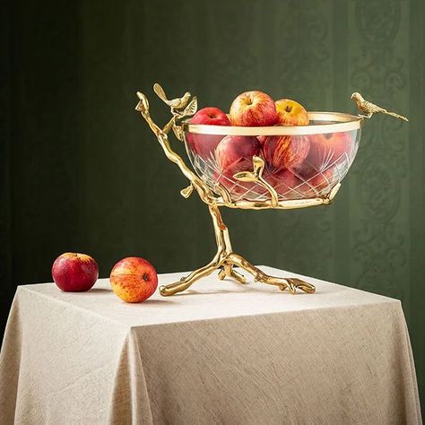 Allow us to present to you our exceptionally twisted European Ornate Tree Glass Fruit Bowl. This fancy piece has a metal base coated in shiny gold. It’s shaped like a lovely tree and has charming bird decorations on it. It’s not only a way to keep your fruits; it’s like having a piece of art right on your table. The glass is of really good quality, so it makes your fruits look great. The tree and bird design gives it a nature-inspired look. It’s more than just a fruit bowl; it’s a piece of ar... Modern Fruit Bowl, Bird Decorations, Elegant Tray, Fruit Plates, Gold Bowl, Pretty Trees, Living Room Ornaments, Glass Fruit Bowl, Glass Fruit