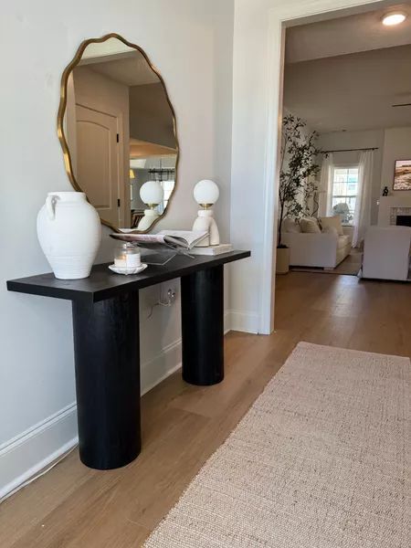 Organic modern entryway inspiration! Featuring a wavy mirror, black console table, and an organic modern lamp that’s budget-friendly. Complete the look with a jute runner, a no-shed jute blend rug, a stylish candle, and some affordable decor to elevate your console table. Entryway Table With Mirror, Organic Modern Entryway, Modern Entryway Ideas, Black Entryway Table, How To Style A Console Table, Entryway Styling, Entryway Table Modern, Entryway Style, Console Table Styling