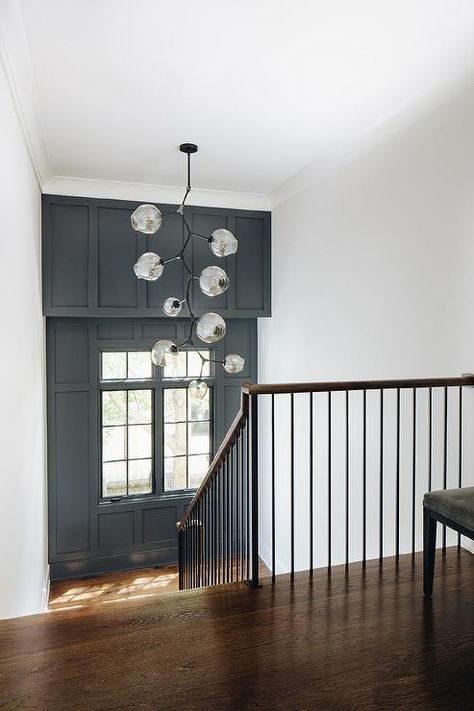 Staircase landing features an accent wall with black paint and wainscoting. Stair Landing Accent Wall Ideas, Landing Feature Wall, Feature Wall Stairwell, Black Feature Wall Staircase, Feature Wall On Stairs, Feature Staircase Wall, Black Accent Wall Stair Landing, Stairway Accent Wall With Window, Black Accent Stair Wall