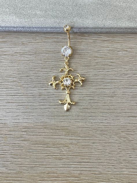 This gold cross belly button ring is beautiful and ornate. Made with surgical steel and coated in 14k gold, this belly button ring dangles with a beautiful cross charm, giving it a gorgeous sparkle, and making it practical for everyday wear. Perfect belly button / navel piercing. Drop jaws with this body jewelry. Details & Size: ♥ 316L Surgical Steel, 14k gold plated // Silver Option now available too! Silver option is surgical steel, not gold plated ♥ Cubic Zirconia Gems ♥ 10mm bar, 14G ♥ Externally Threaded ♥ Every purchase comes with an Elara gift box For sanitary purposes, piercing items are non-returnable, so please double check sizing and message me if you have any questions! Gold Cross Belly Button Piercing, Gold Piercings Belly, Belly Piercing Jewelry Gold, Cross Belly Ring, Belly Piercing Dangle, Gold Belly Piercing Aesthetic, Cross Belly Piercing, Belly Ring Gold, Belly Button Piercing Jewelry Gold