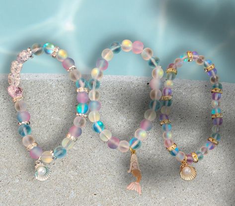 So gorgeous! Perfect for your summer stacks! Mermaid glass, all the rage right now, is a frosted glass that reflects light, picks up so many colors, and appears to shimmer. The colors and their shimmer are reminiscent of the sea and the sky.   Each bracelet can be worn alone or added to a stack.  The Mermaid bracelet is 6.30 inches relaxed. It is made of blue, white, blue/pink gradient, and 1 pink mermaid glass bead. The beads are 8MM. The mermaid charm is gold-plate with pink, white, and bronze enamel. The Gold Shell bracelet is 6.30 inches relaxed. It is made of 6mm blue, white, and purple mermaid glass beads with gold crystal rondelle accents. The shell charm is gold-plated with white a acrylic pearl in the center. The Blue Silver Shell bracelet is 6.70 inches relaxed. It is made of 8mm Purple Mermaid, Mermaid Glass, Mermaid Bracelet, Pink Mermaid, Diy Bracelets Easy, Small Gift Bags, Shell Bracelet, Crackle Glass, Glass Bracelet