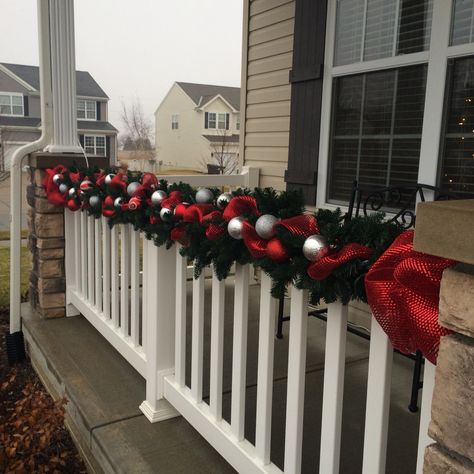 Garland on the front porch. Garland On Front Porch Pillars, Christmas Porch Banister Decorations, Porch Railing Christmas Decorations, Balcony Ideas Christmas, Outdoor Christmas Balcony Ideas, Outdoor Banister Christmas Decor, Patio Decorating Ideas Christmas, Garland On Fence Christmas, Apartment Outdoor Christmas Decor