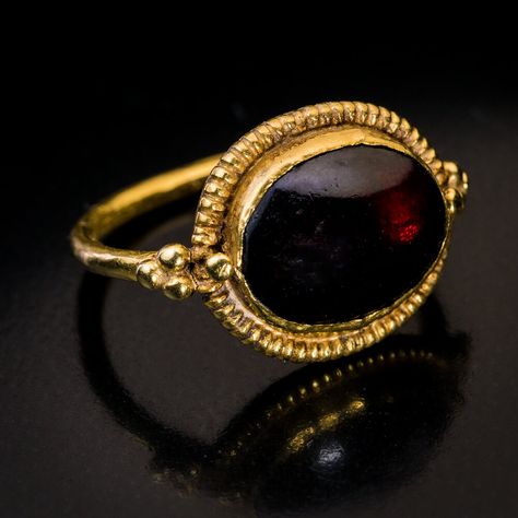 Ancient Byzantine Cabochon Garnet High Karat Gold Ring. This early Byzantine ring, circa 5th-6th centuries CE, is finely crafted in 21 karat gold. The ring features an oval cabochon cut garnet of a deep red color set in a ribbed bezel and flanked at the shoulders by gold beads. Ancient Rings Jewelry, Byzantine Jewelry Ancient, Historical Rings, Ancient Rings, Antique Gold Ring, Byzantine Ring, Ancient Roman Jewelry, Byzantine Gold, Byzantine Rings