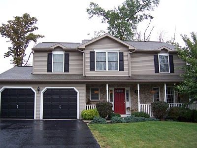 A while ago, I had mentioned that we wanted to eventually redo the outside of our house. Read about it here . Just a reminder of what our house looked like last week: Not bad, just not “us”! We hadn’t planned on doing anything just yet because of several factors, the biggest factor being money … Black Garage Doors, Red Door House, Front Of A House, Garage Door Colors, Tan House, Red Doors, Red Front Door, Black Shutters, House Shutters