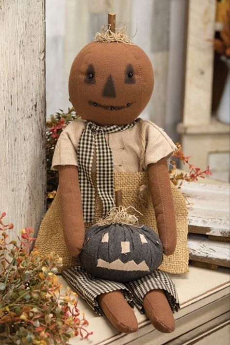 Our Primitive Pumpkin Girl doll holds a gray pumpkin with a beige Jack O Lantern design. Her pumpkin head has a beaded face and is topped with a tuft of dried moss around a wooden stem. This doll will look great propped against a crate or hay bale in a Halloween display. Measures 23" long by 6.5" wide and includes a string hanger on the back. - Material: Fabric, Wood - Size: 23" L x 6.5" W x 4" D - Color: Burnt Orange, Gray, Tan, Beige, Black - Designer: Dawn Stake Burlap Outfit, Primitive Crafts Diy, Black Jack O Lantern, Prim Halloween, Scarecrow Doll, Black Folk Art, Grey Pumpkin, Pumpkin Girl, Ceiling Trim